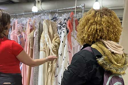 Student and staff member look through prom dresses at Belle of the Ball event