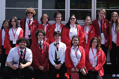 14 students who competed in the SkillsUSA state tournament stand in front of a school van